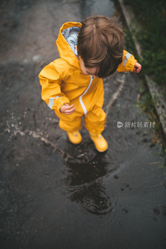 小男孩在雨中玩耍，跳进水里画画