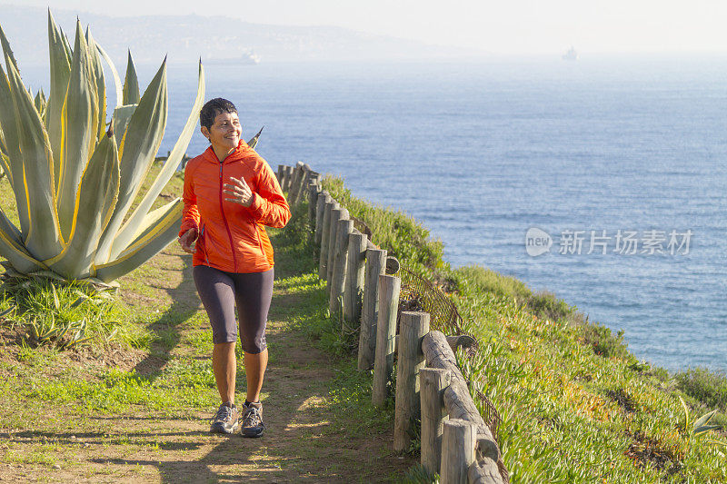 拉丁成年女子沿着海边的木板路跑步