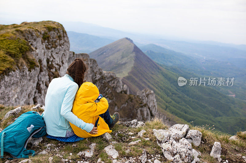 母子徒步旅行者坐在山顶上