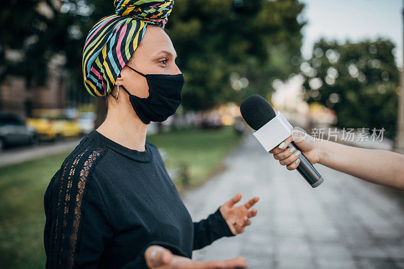新冠肺炎大流行期间，一名年轻女子在街头接受记者采访
