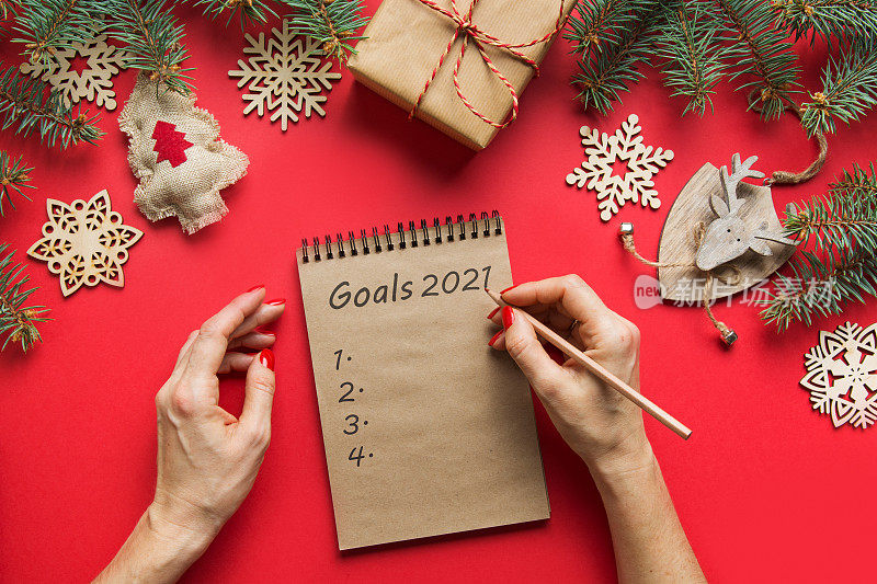 在手工笔记本上写新年目标和计划的女人。从以上观点。