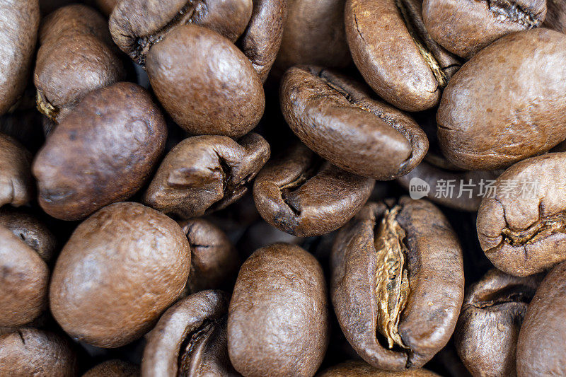 微距拍摄咖啡豆背景。近距离观察咖啡豆。新鲜烘焙的深棕色阿拉比卡咖啡豆质地背景。俯视图