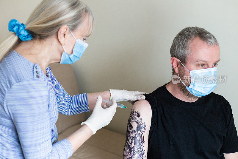 袖上纹身的男子向医生接种Covid-19疫苗