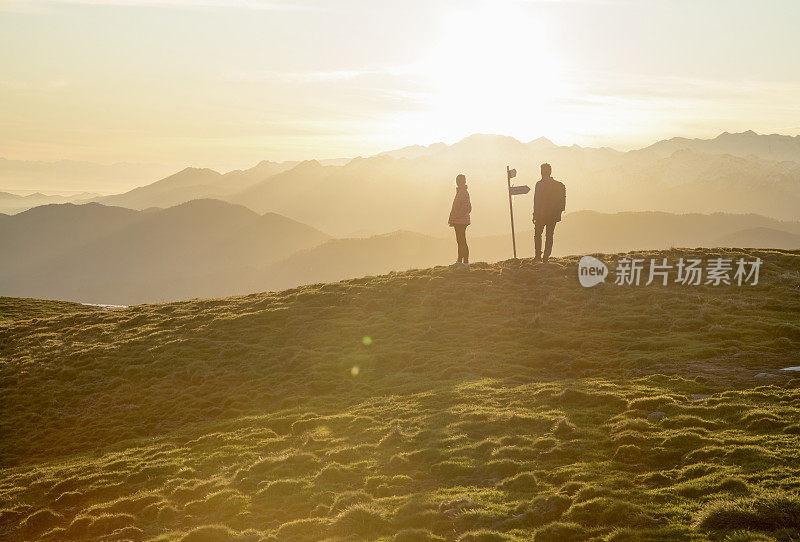 夫妇走在高高的草地上，路标