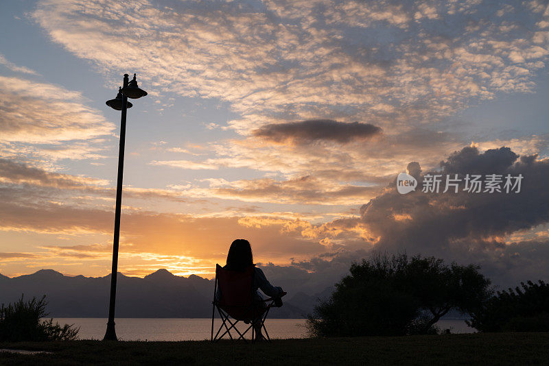 日落时坐在露营椅子上的女人剪影