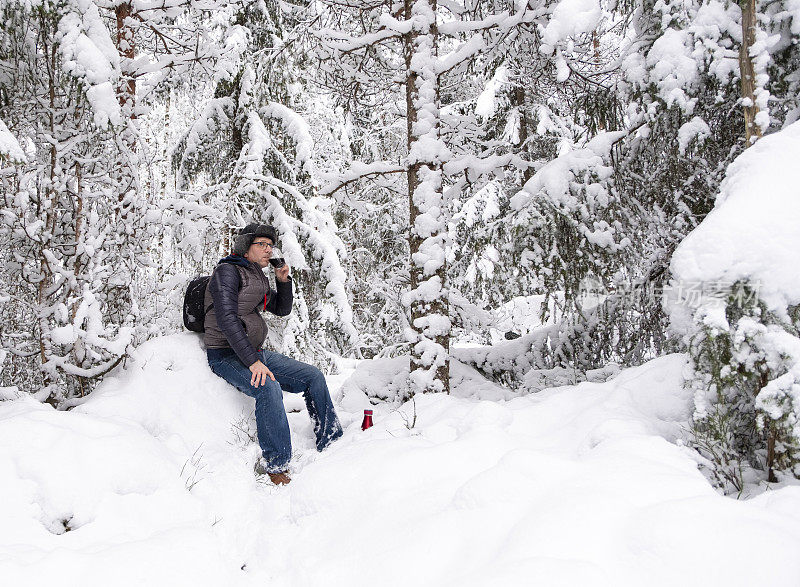 一个男人在白雪覆盖的森林里喝咖啡。男,中年白种人。步行旅游。
