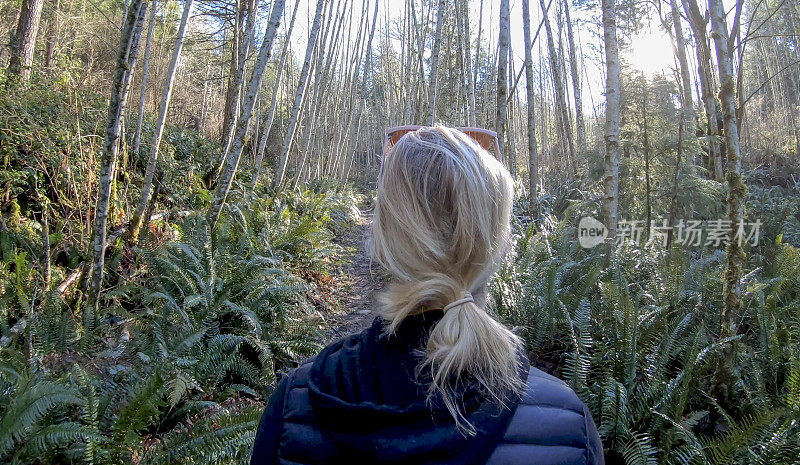 女人穿过茂密的森林走进阳光