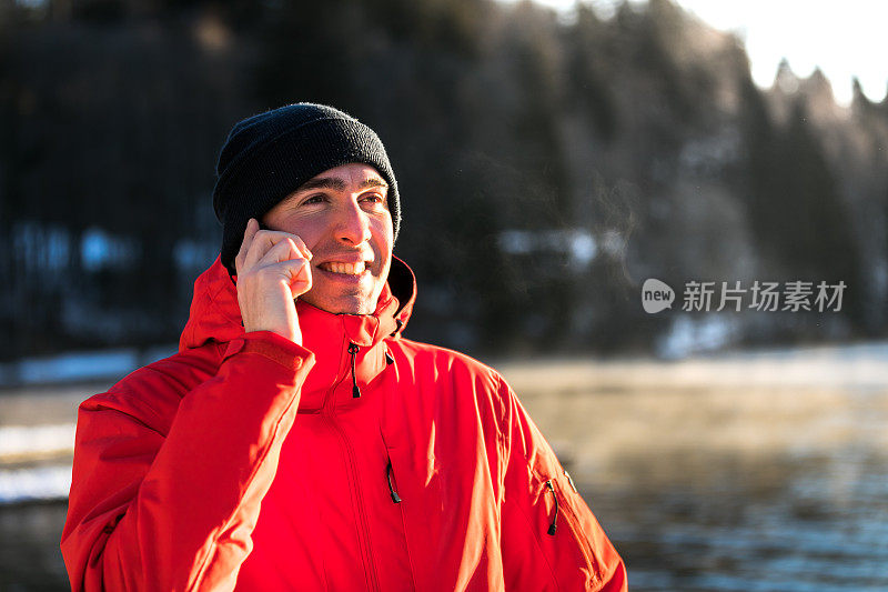 一名男子在湖边使用智能手机。