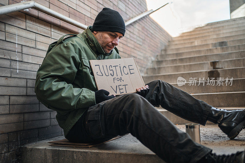 无家可归的退伍军人拿着一个写着“为兽医伸张正义”的牌子乞讨