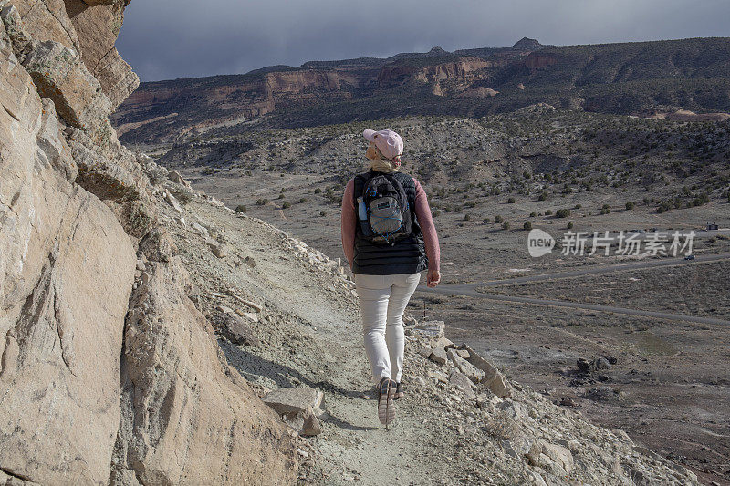 女性徒步旅行者在早晨穿过阳光明媚的山脊