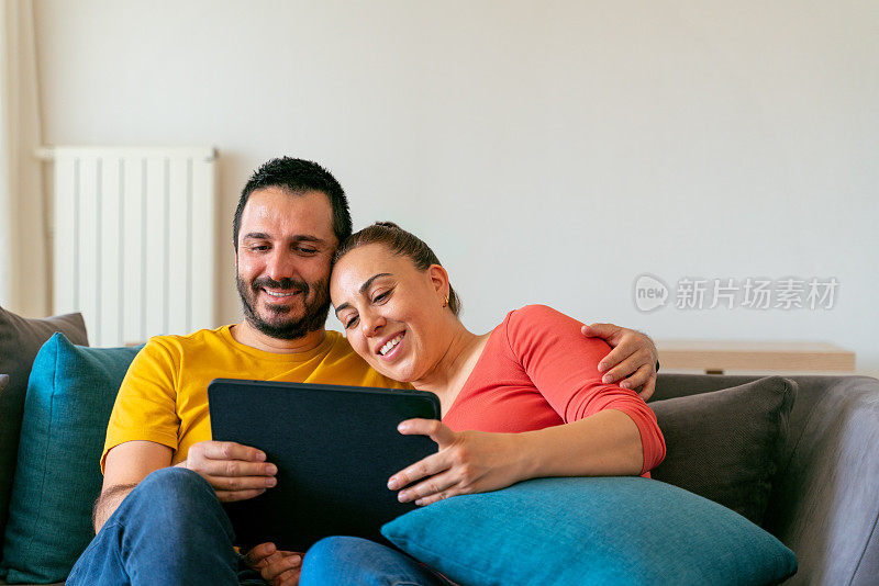 一对年轻夫妇在客厅看平板电脑