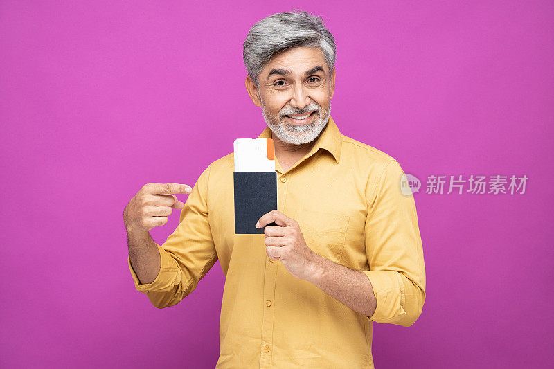肖像英俊的成熟男子显示护照与票站在孤立的粉红色背景:库存照片