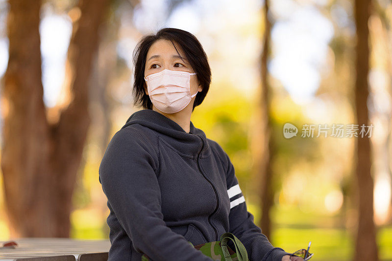 坐在户外戴口罩的妇女。