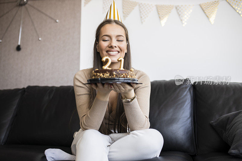 年轻漂亮的女人在家里用巧克力蛋糕庆祝她21岁的生日