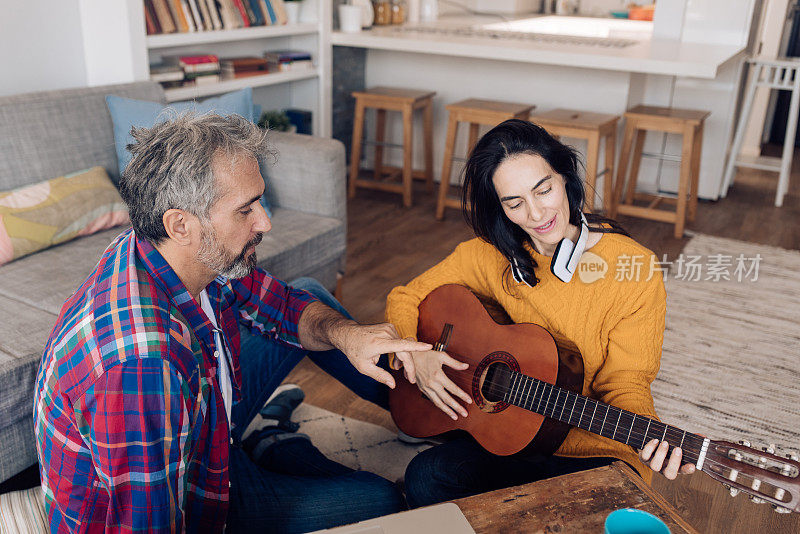 成熟的女人喜欢在家和丈夫一起学习弹吉他