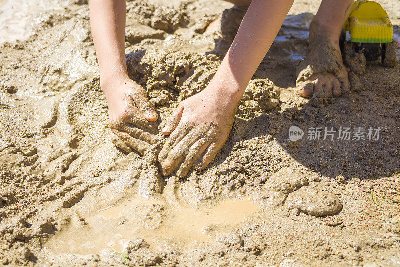 光着脚的孩子在湿沙上玩耍。小男孩在夏日阳光明媚的日子里揉捏泥巴做模型