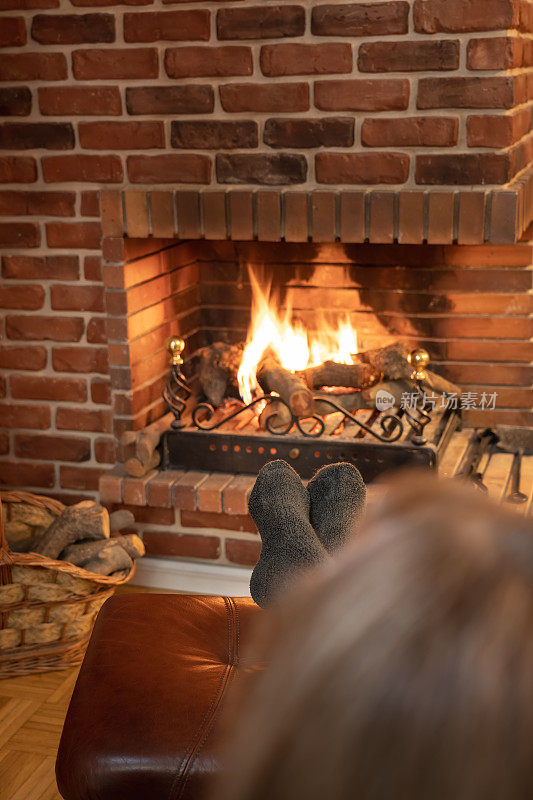 一个女人在冬天舒舒服服地躺在壁炉的火炉前。