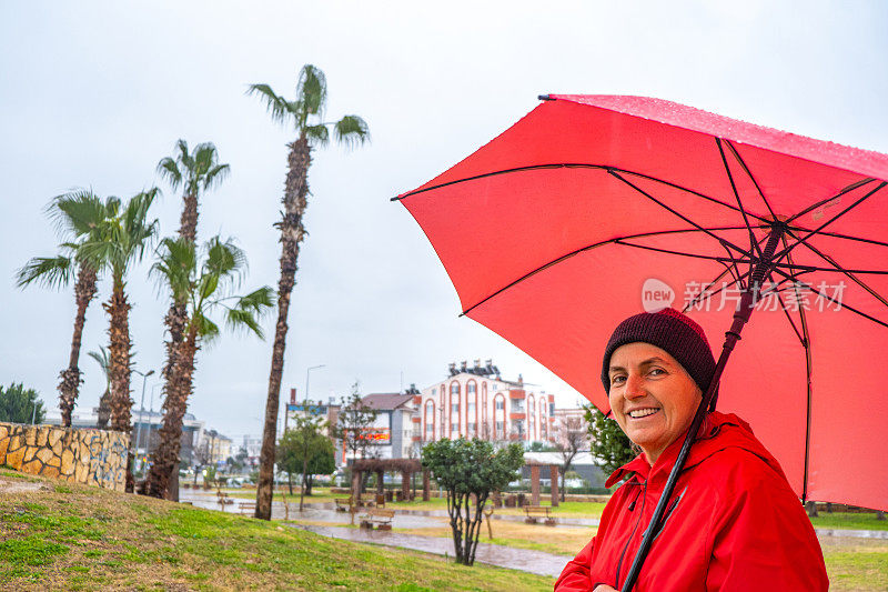 在雨天撑着雨伞散步的女人微笑着看着镜头。肖像