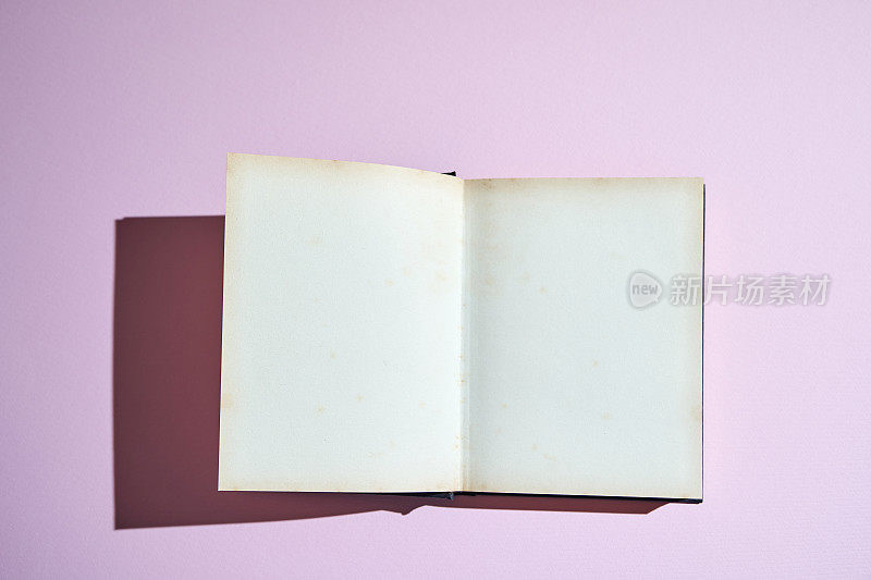 空白打开书与硬阴影粉红色背景