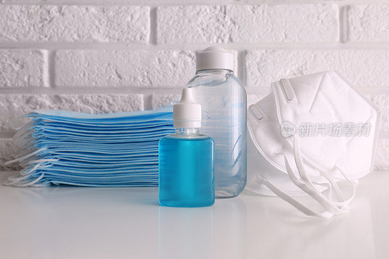 白砖墙旁的桌子上放着洗手液和呼吸面罩。COVID-19大流行期间的防护必需品