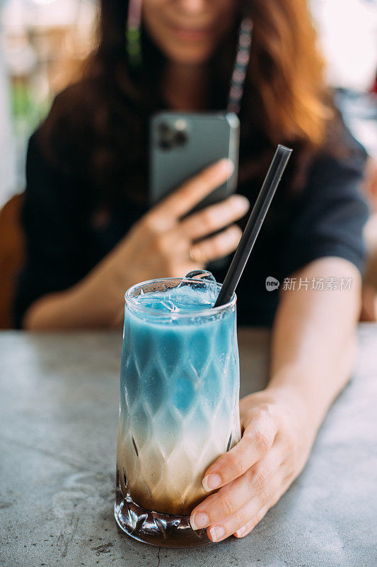 用智能手机拍一杯蓝色抹茶冰拿铁