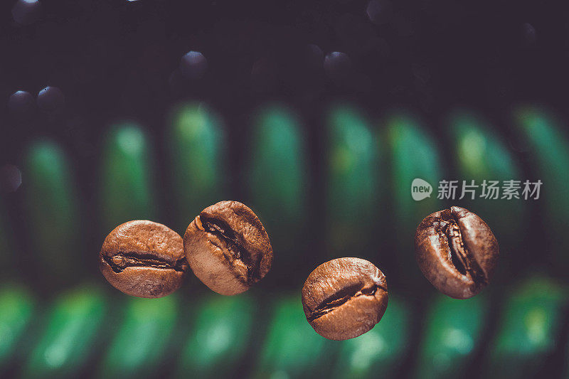 咖啡豆在闪亮的黑色背景下的特写。咖啡豆在绿叶背景。咖啡的背景。用咖啡豆复制空间。咖啡豆放在餐桌上。咖啡豆的特写