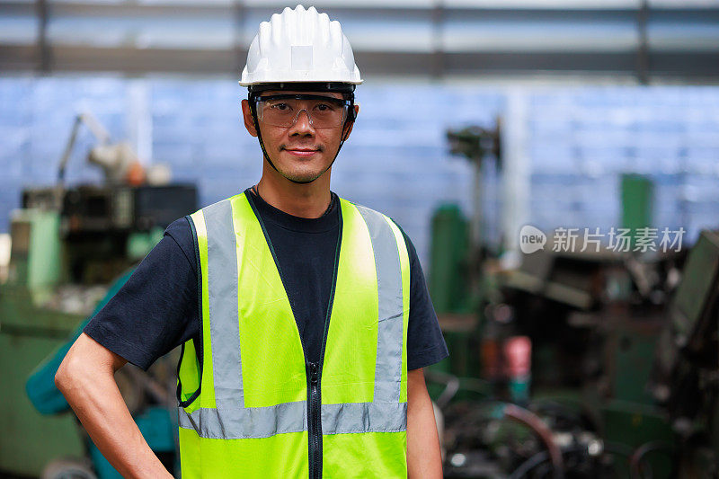 肖像亚洲男子工人看相机。重工业制造中的金属机械。亚洲男工厂工人戴安全帽安全帽