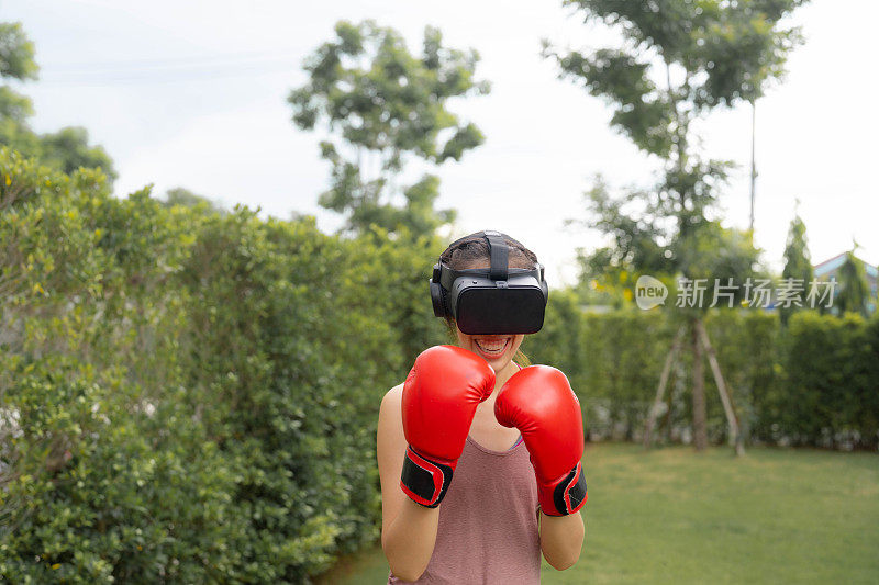 年轻的拳击手妇女戴着虚拟现实头盔在公园里练习。