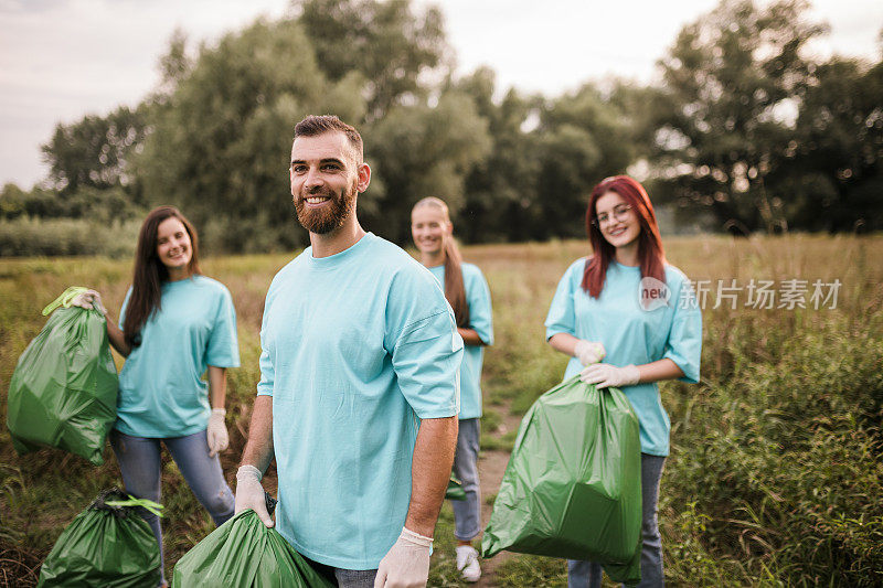 一群人志愿，慈善，清洁，人与生态的理念-一群快乐的志愿者用垃圾袋清扫公园区域