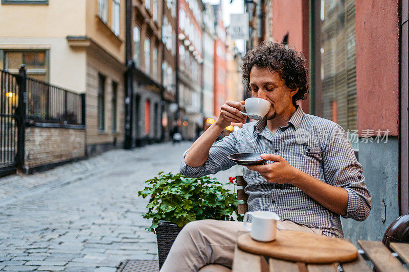 在人行道上喝咖啡的年轻人Café