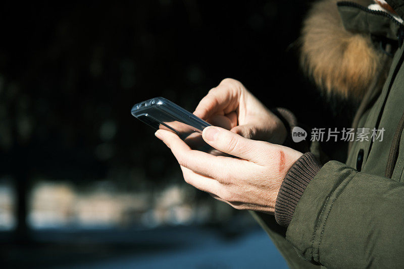 在冬季小镇，一个女人用智能手机的手