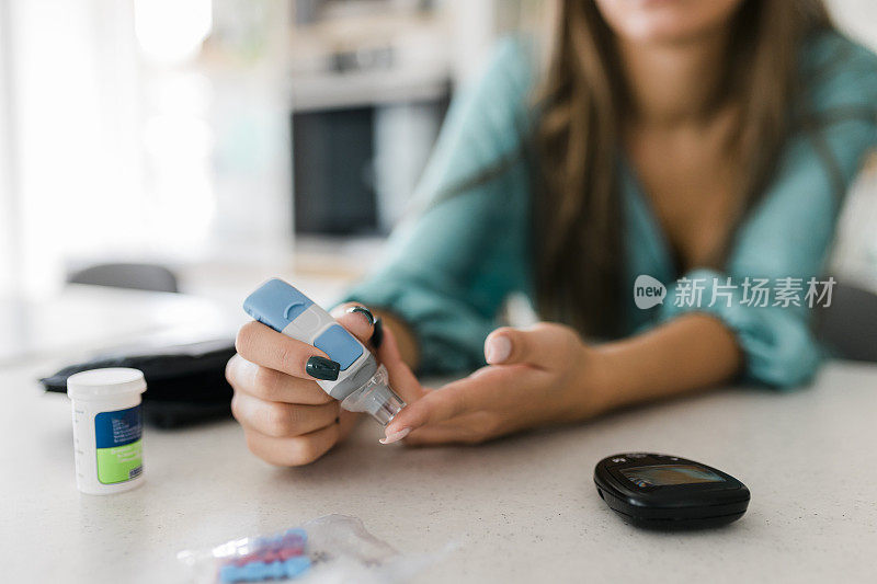 近距离的妇女使用柳叶刀在手指上检查血糖水平的血糖仪，保健和医疗，糖尿病，血糖概念