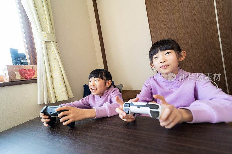 两个小姐妹在一起玩电子游戏