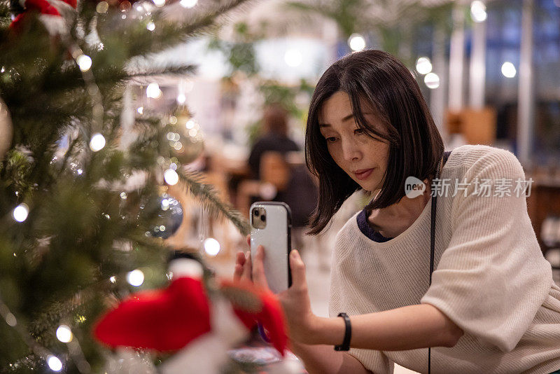 女人在咖啡馆里拍圣诞树的照片