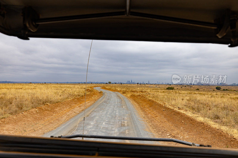 空旷的道路在肯尼亚的草地景观中，透过挡风玻璃看到