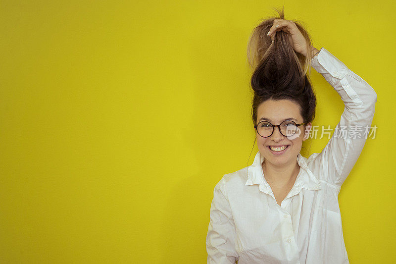 美丽的微笑女人看着相机，同时把她的头发