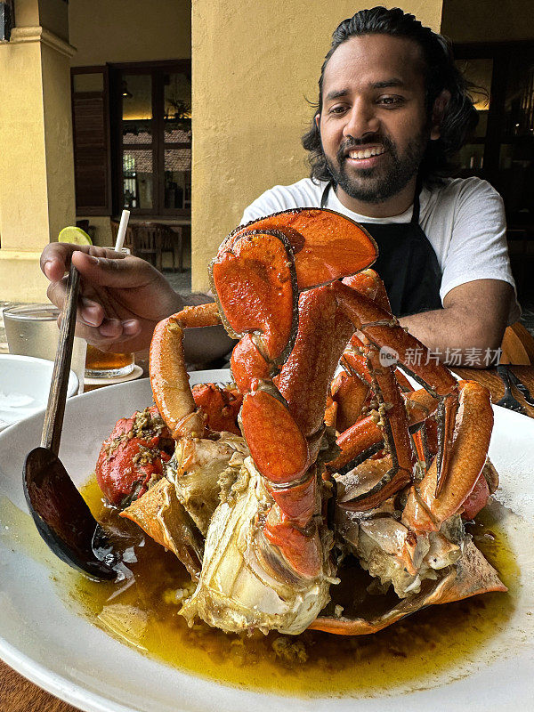 印度一家海鲜美食餐厅，新鲜出炉的整只泥蟹，配上带壳的蒜蓉黄油酱，男人用勺子浇在上面