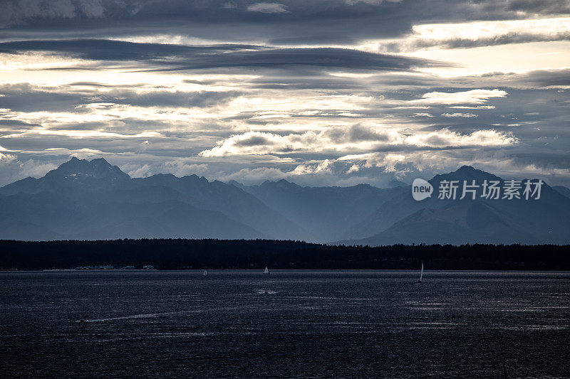 美丽的海洋与山脉为背景，在蓝色的阳光照耀下，阴云密布