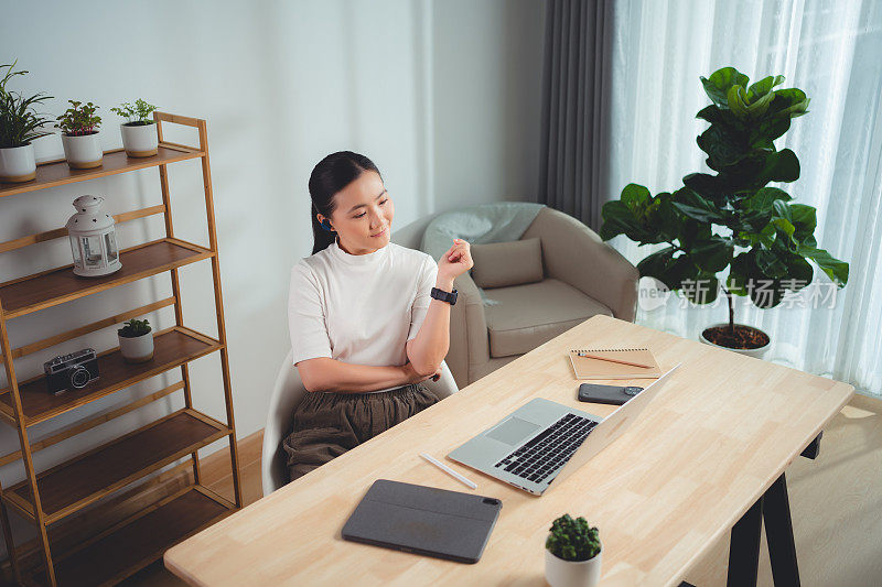 亚洲女性喜欢用笔记本电脑在线工作，坐在家里开会。