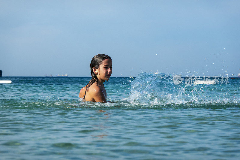 他用手在海里泼水。一个夏天的早晨。忒涅多斯岛。爱琴海北部，12岁的帅哥。长头发的