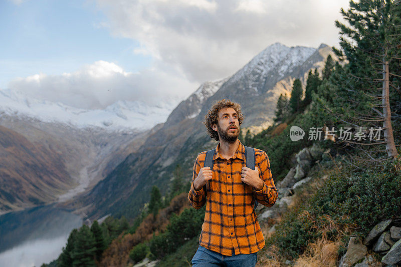 一名男子在湖泊和山脉环绕的欧洲阿尔卑斯山徒步旅行