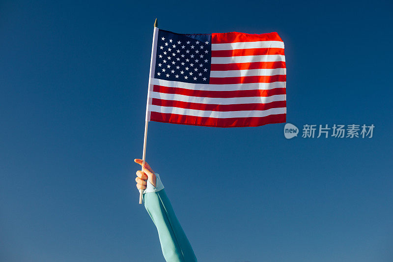 在蓝天上挥动美国国旗的手