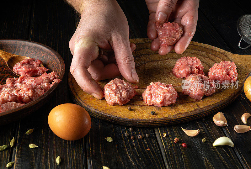 厨师用手把一个肉丸放在厨房板上。在厨房桌子上准备午餐的肉。烹饪食谱和营养概念