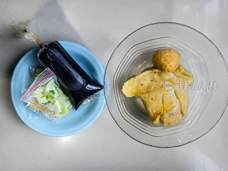 彭派克盛在碗里，小盘子里放着醋酱。Pempek是一种来自苏门答腊岛巨港市的典型印尼食物。由鱼和木薯粉制成