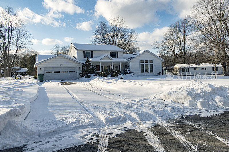 下雪的冬季汽车轮胎印离开郊区住宅车道