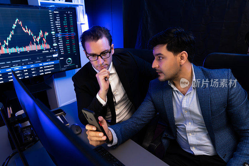 两个证券交易所的交易员在智能手机和笔记本电脑上研究数据。适于销售的。