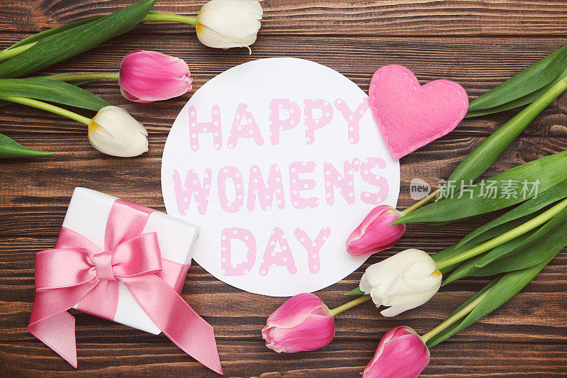 花的郁金香，心，礼盒和圆形卡片与文字妇女节快乐在棕色木制背景