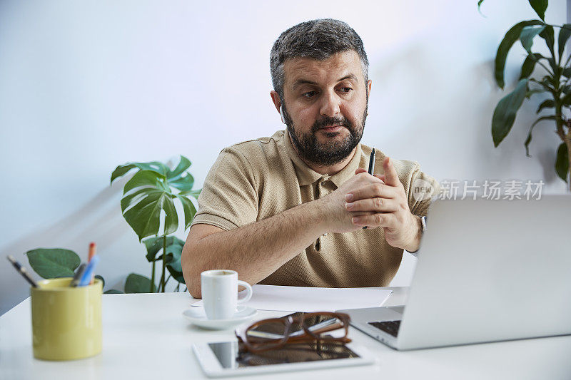 一个年轻人在他的家庭办公室里对着电脑说话