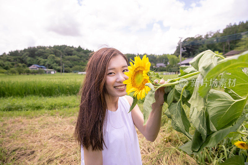 年轻女子的肖像站在向日葵在农场