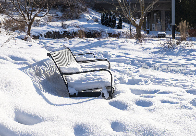 城市公园里的冬天，花园长椅上白雪覆盖。芬兰科特卡市的城市公园。